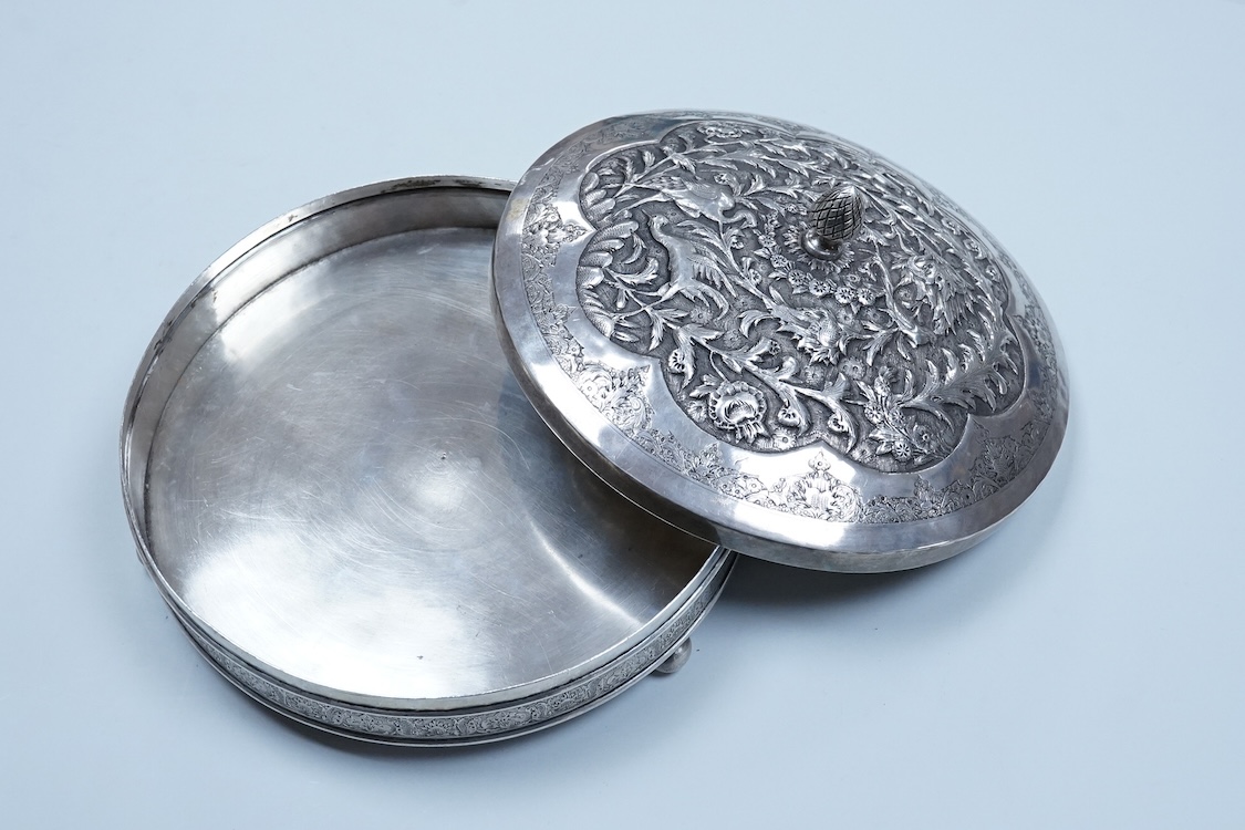 A 20th century Middle Eastern white metal circular box and cover, decorated with birds amongst foliage, base diameter 21.8cm, on three bun feet, 31.7oz.